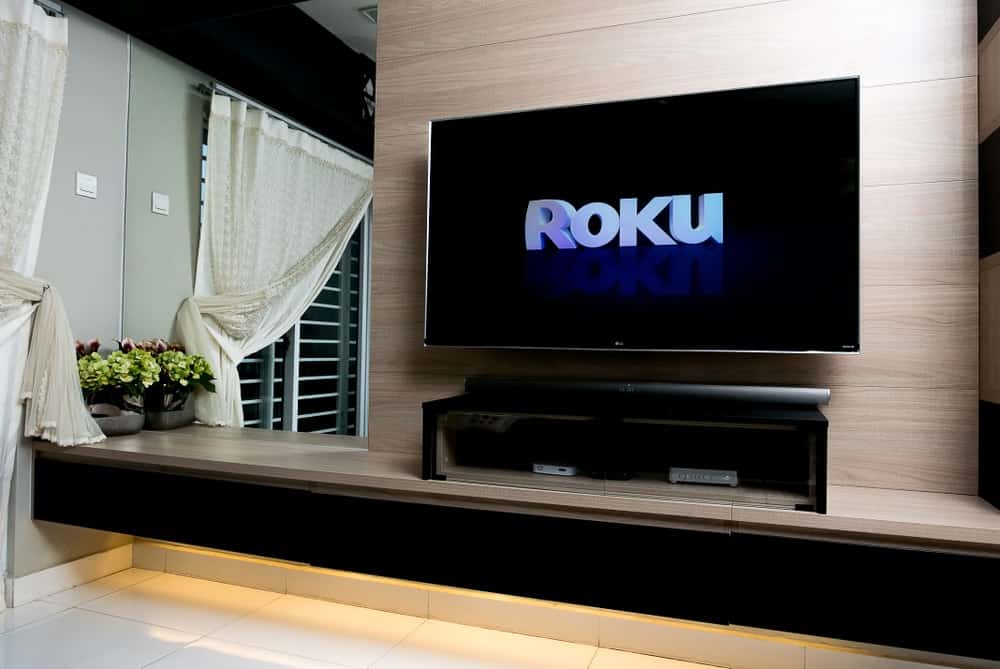 A wall-mounted smart TV showing the logo for Roku.