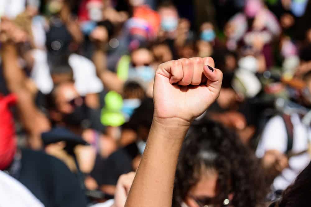 A woman pumping her fist in the air at a human rights rally.