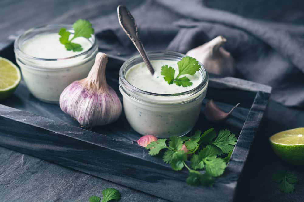 Cilantro garlic sauce with lime juice and olive oil in a glass jar.