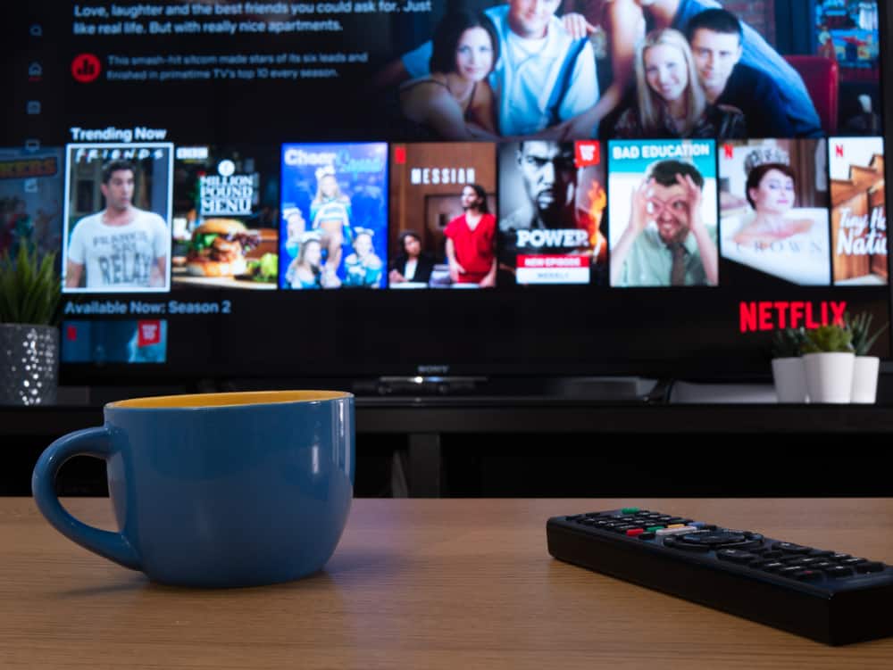 A close look at a cup of coffee on a wooden coffee table across from the TV that features Netflix.