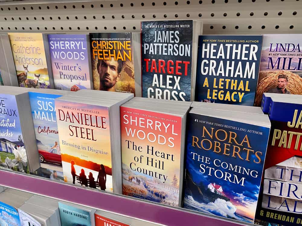 Variety of fiction books on a shelf inside a store.