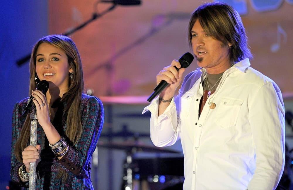 Miley Cyrus and her father on stage performing.