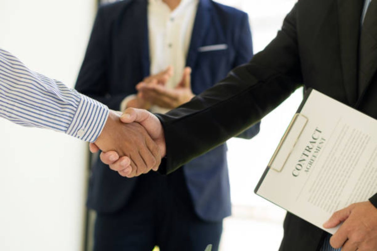 A photo of two man in a formal meeting shaking their hands.